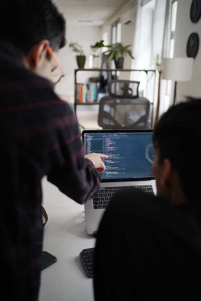 Two developers reviewing code on a laptop